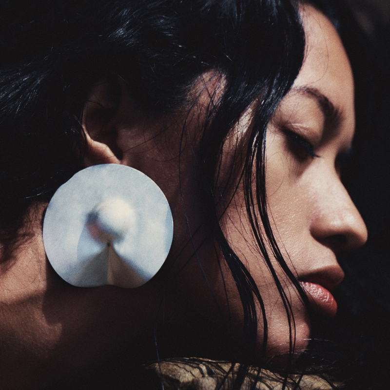 Woman wearing large circular disc earring, profile view
